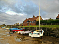 A boat yard with an elevated grass bank that has a house.